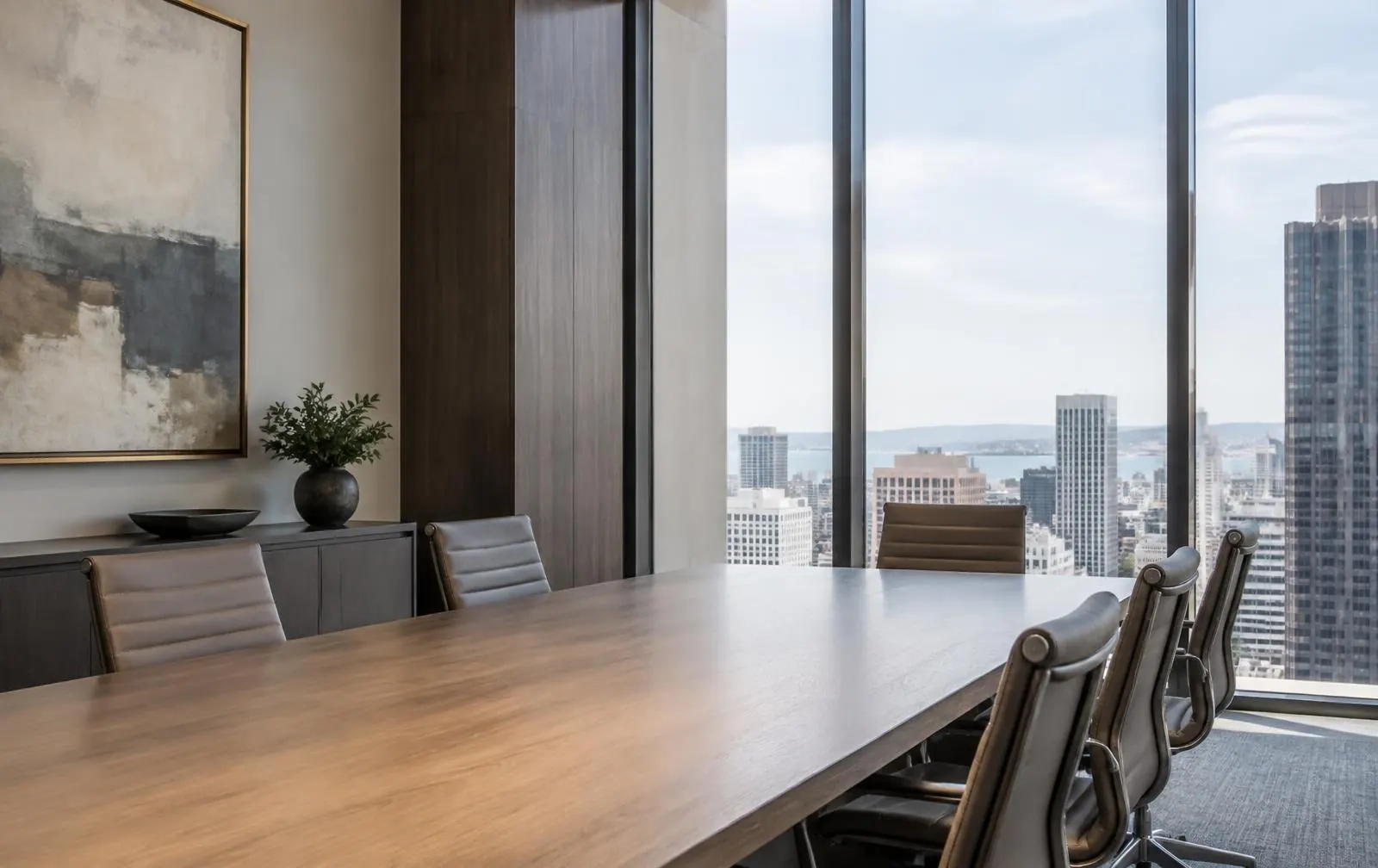 Quiet boardroom with a long table and a wide city view